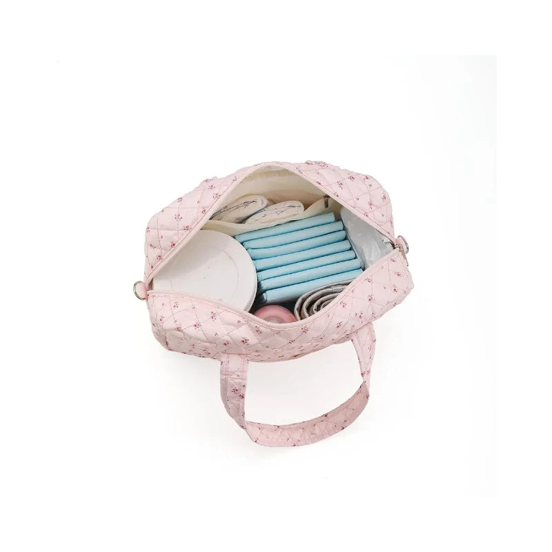 Compartiments intérieurs du sac à langer fleuri avec biberon et lingettes